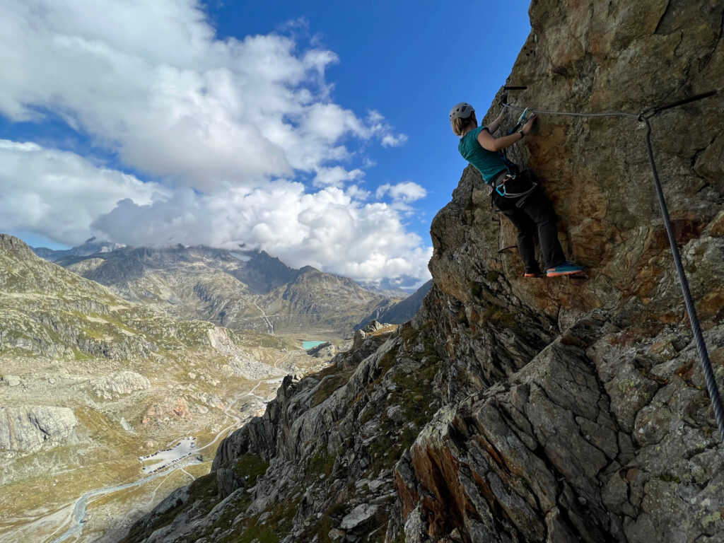 Junge Frau klettert in einem Klettersteig.