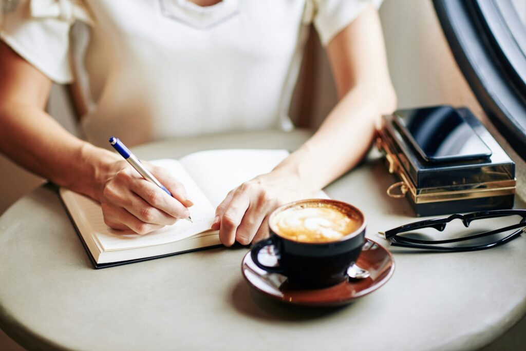 Woman writing in Notebook. Young girl taking notes in Journal. Journaling.